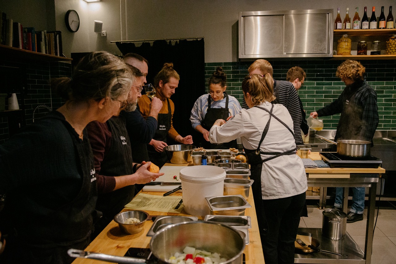 Enthusiastische Kochkurs-Teilnehmer bei der Zubereitung von Gerichten unter Anleitung eines Chefkochs im Studio 32.